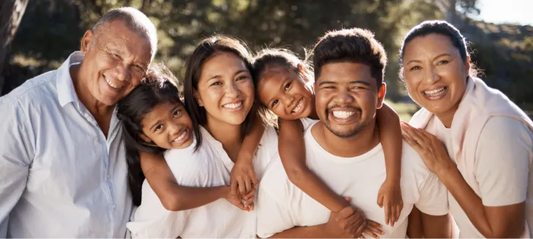 Three generations of a family smiling in the sunlight